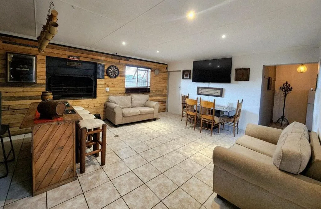 Spacious lounge with beige sofas, wooden feature wall, and wall-mounted TV