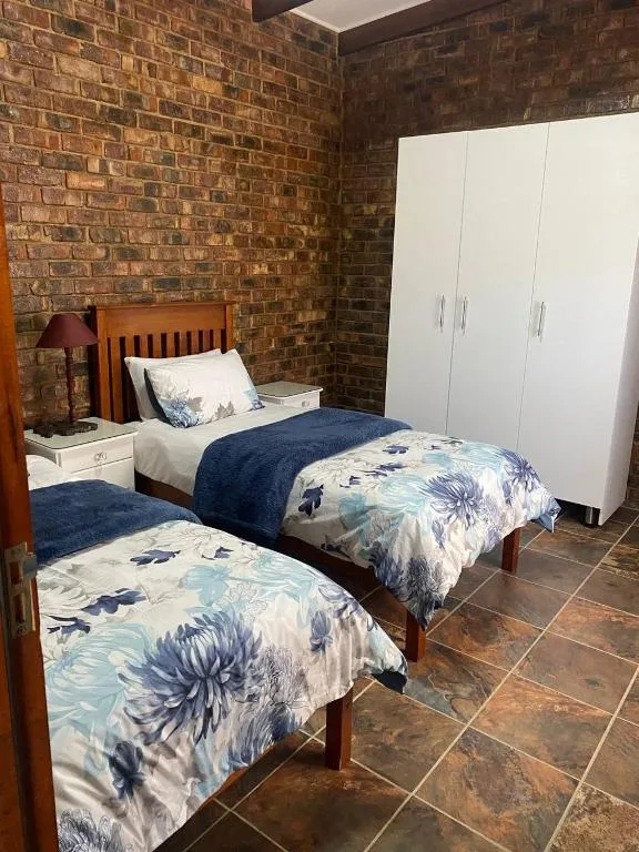 Twin bedroom with floral bedding, brick walls, wooden furniture, and storage