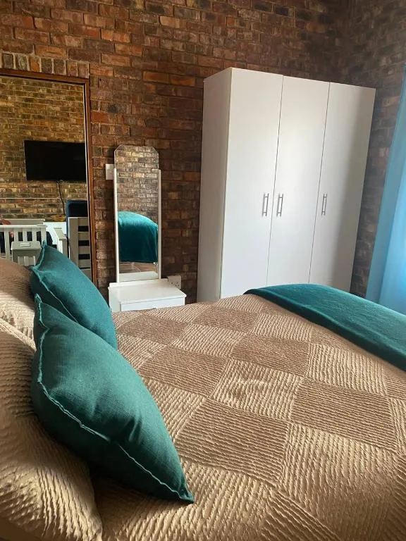 Spacious bedroom with bed, white wardrobe, and exposed brick walls