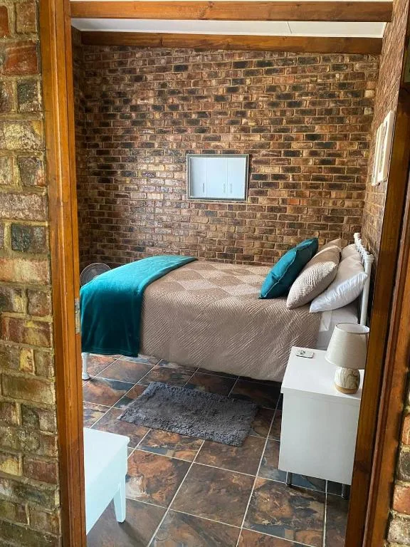 Cozy bedroom with teal and cream bedding against exposed brick wall