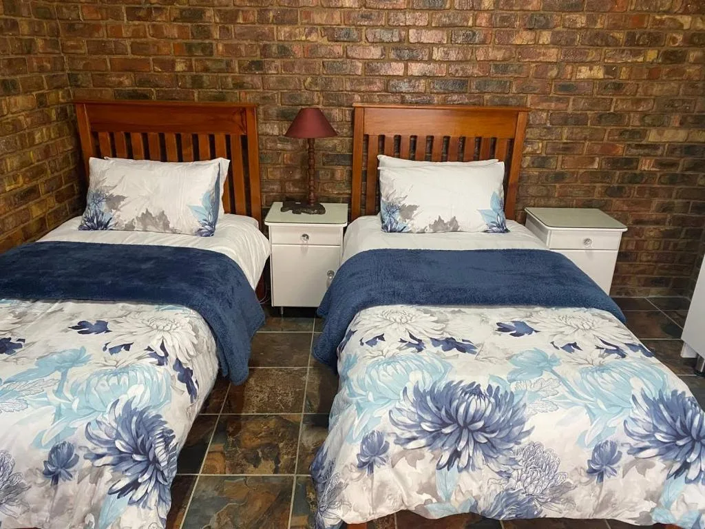 Twin bedroom with wooden headboards and floral bedding against brick walls