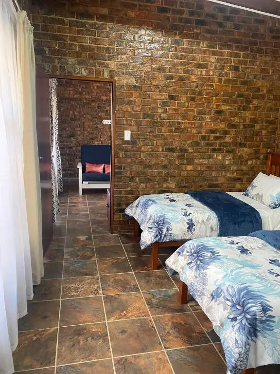 Twin beds with patterned blue bedding in brick-walled bedroom