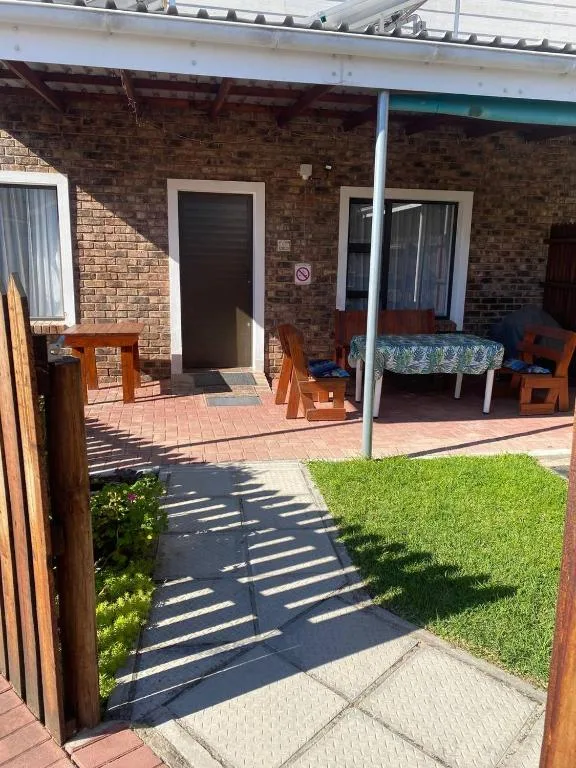 Brick patio with outdoor seating and lawn area in afternoon sunlight