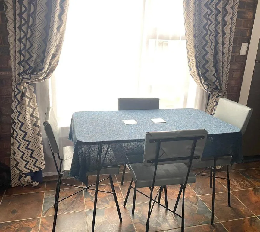 Compact dining table with four chairs near window with patterned curtains