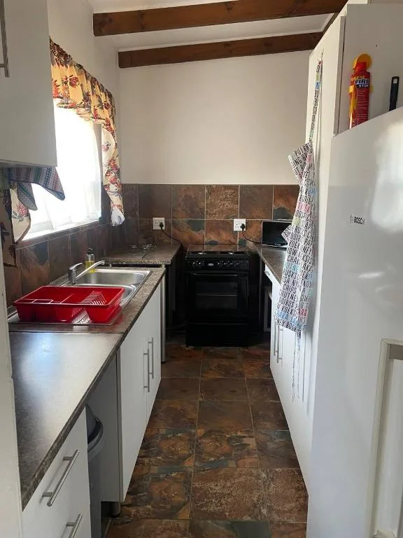 Compact kitchen with black stove, sink, and white cabinetry