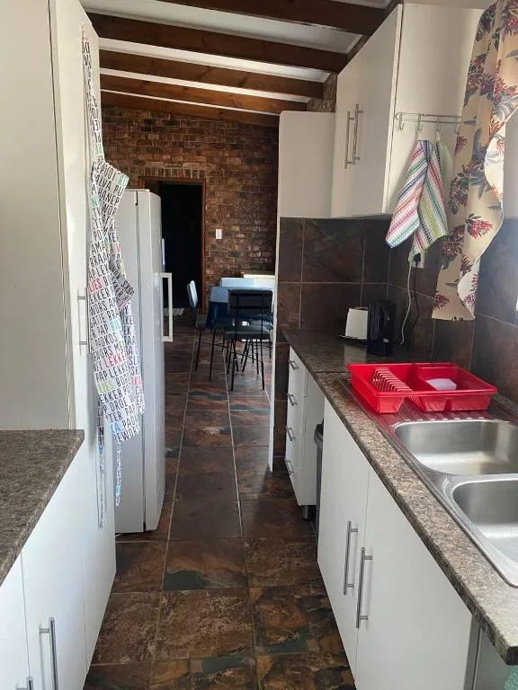 Galley kitchen with white cabinetry, granite countertops, and stainless steel sink
