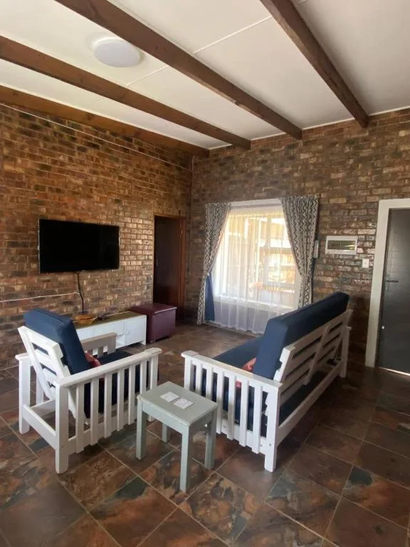 Spacious lounge with exposed brick walls and wooden beams, comfortable seating