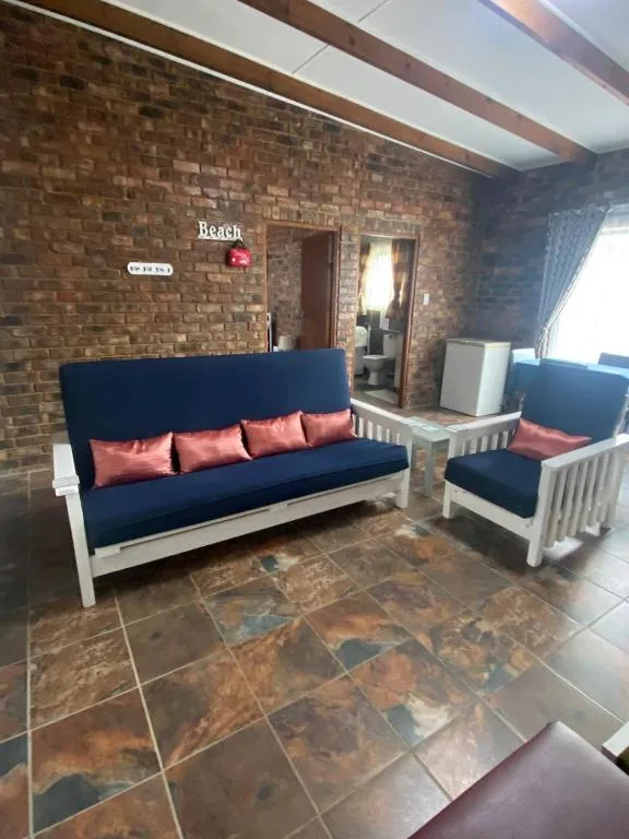 Spacious lounge with navy sofa, coral cushions, and brick walls