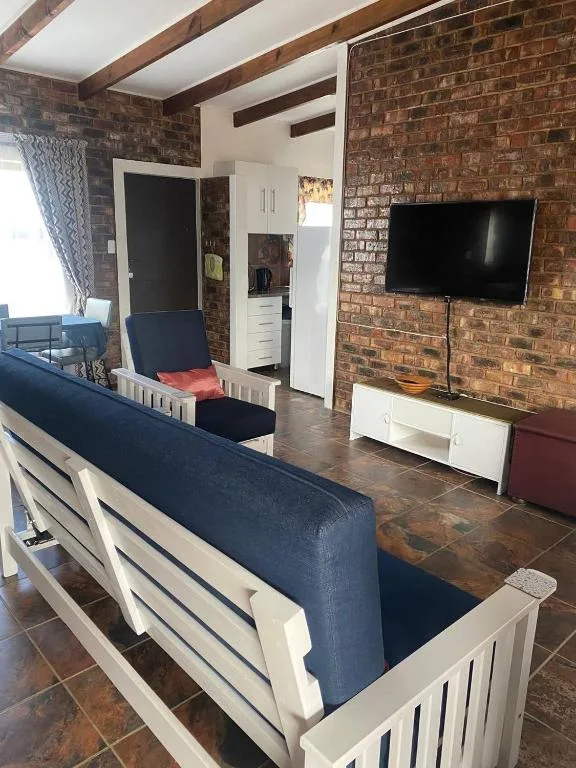 Open-plan lounge with exposed brick walls, navy sofa, and wall-mounted television