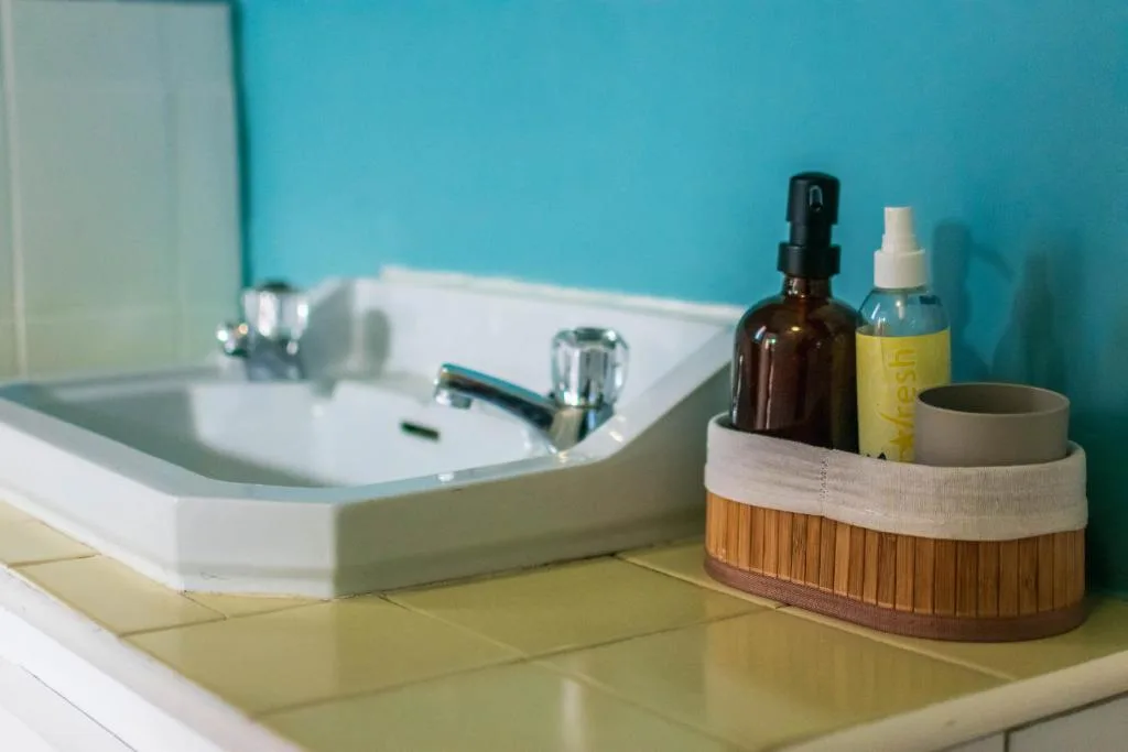 Modern bathroom vanity with white curved sink and turquoise wall