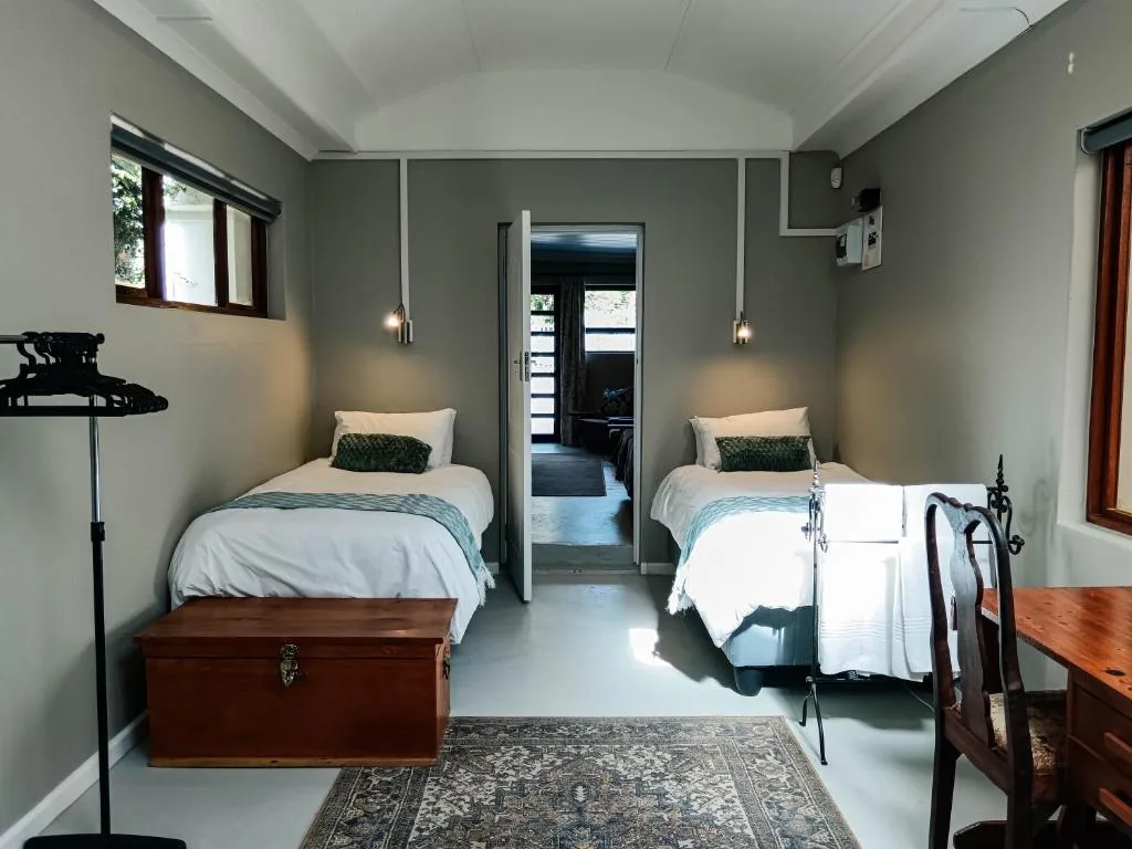 Twin bedroom with white bedding, pendant lights, and wooden trunk
