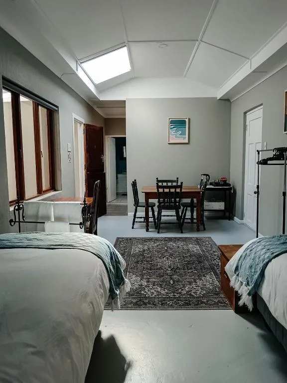 Bright bedroom with two beds, skylight, and open-plan living area visible