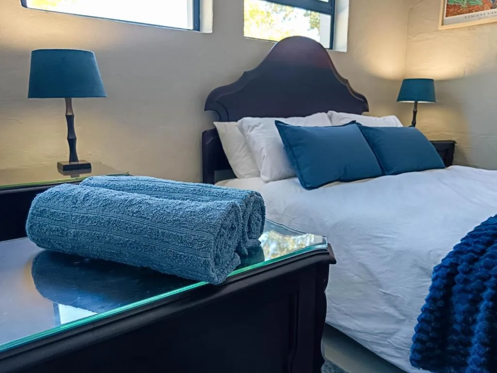 Master bedroom with dark headboard, blue pillows, white linens, and bedside lamps