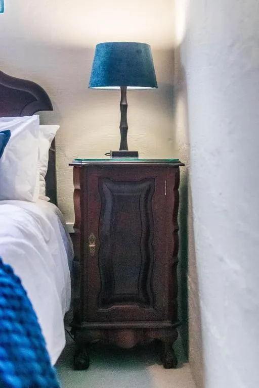 Bedroom nightstand with blue lamp and wooden cabinet beside bed