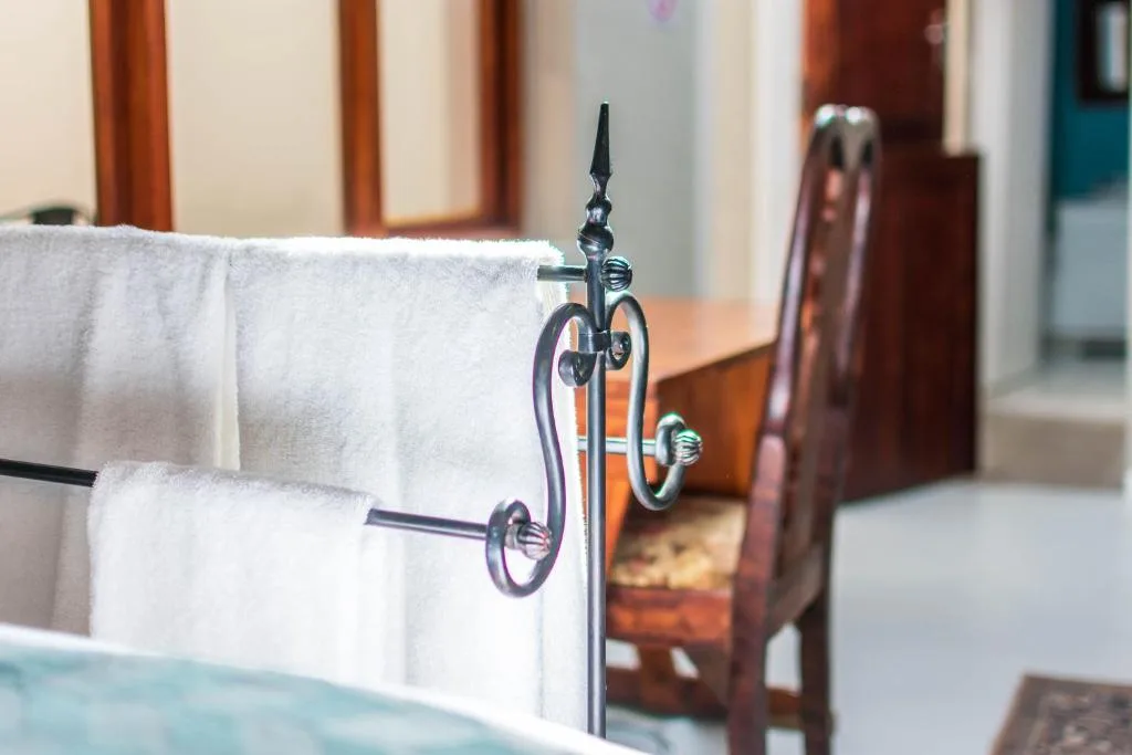 Decorative towel rail with white folded towels in bedroom