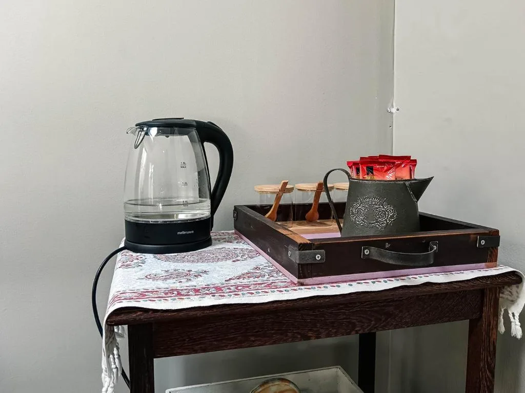 Electric kettle and decorative items on wooden bedroom table