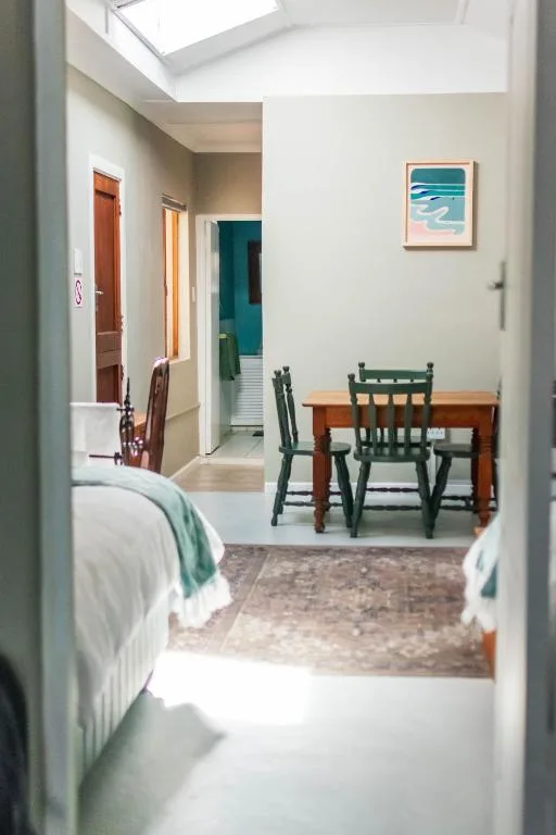 Open-plan interior showing bedroom, dining table, and bright skylight above
