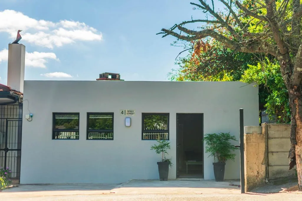 White modern apartment facade with dark-framed windows and potted plants