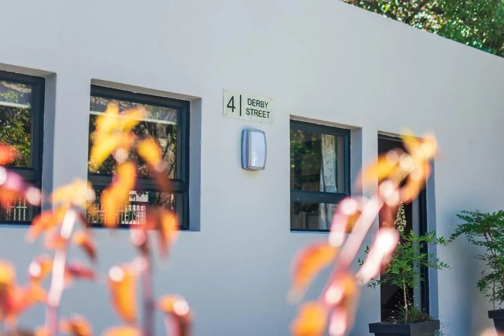 Modern white building facade with dark-framed windows and Derby Street address sign