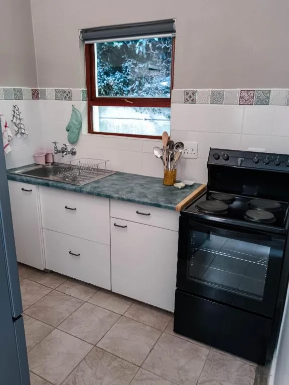 Kitchen with white cabinetry, black electric stove, and marble countertop