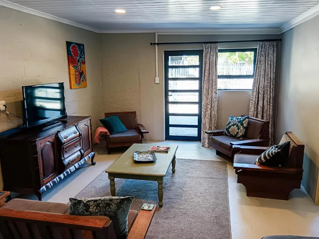 Spacious living room with brown leather sofas, TV, and glass doors