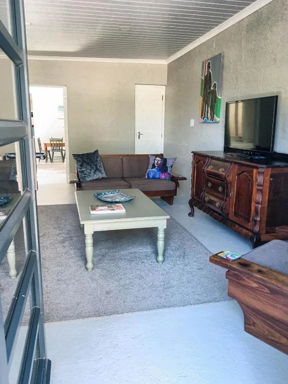 Living room with brown sofa, TV on wooden stand, and white coffee table