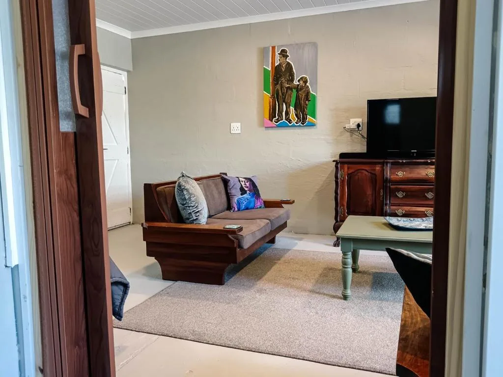 Living room with wooden sofa, TV, and colorful wall art