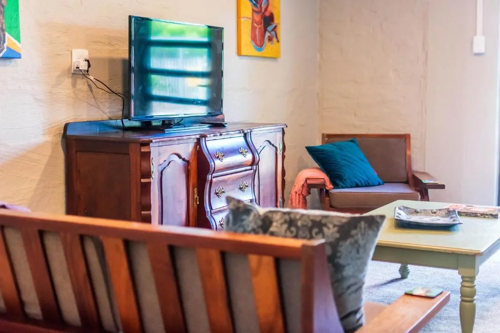 Living room with TV, wooden furniture, colorful artwork, and comfortable seating