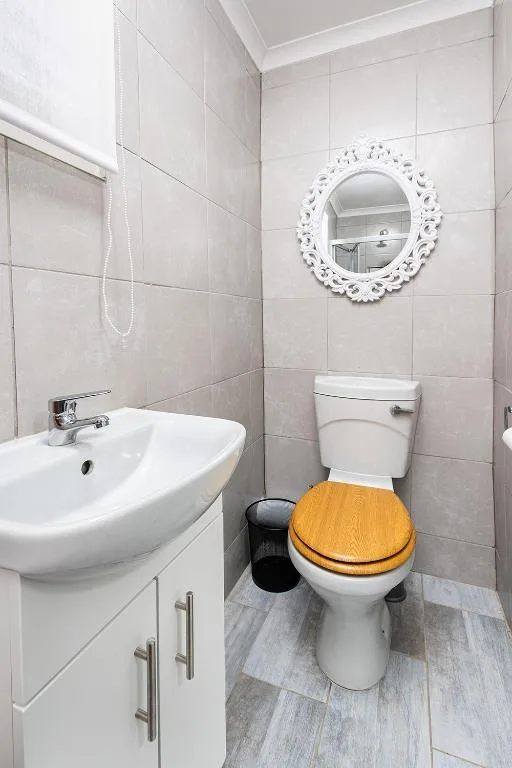 Clean bathroom with white sink, toilet, and decorative mirror