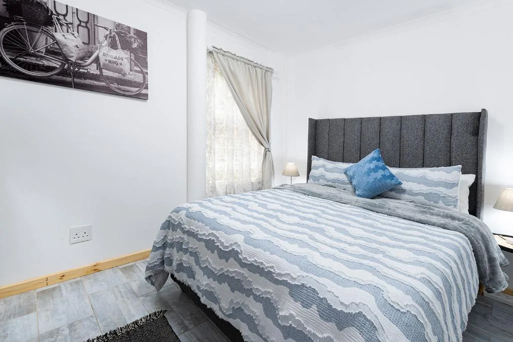 Bright bedroom with gray upholstered headboard and striped blue bedding