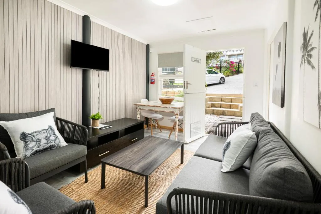 Modern lounge with gray sofas, wall-mounted TV, and garden view