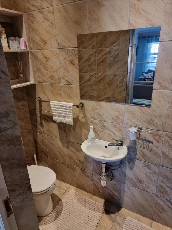 Modern bathroom with marble tiles, sink, toilet, and glass shower enclosure