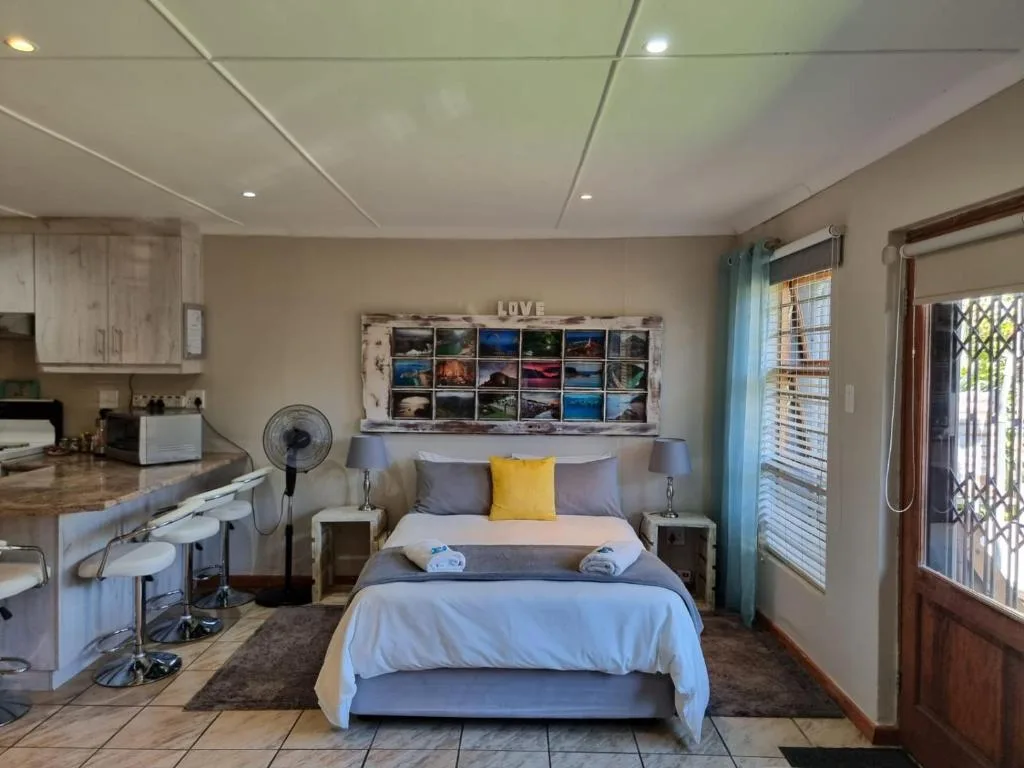 Open-plan bedroom with double bed, kitchen area, and glass doors to outdoors