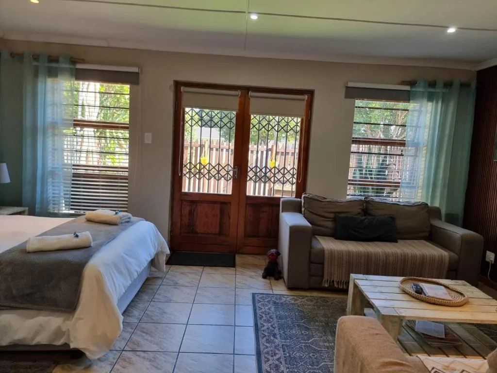Spacious bedroom with bed, sofa seating area, and garden views through French doors