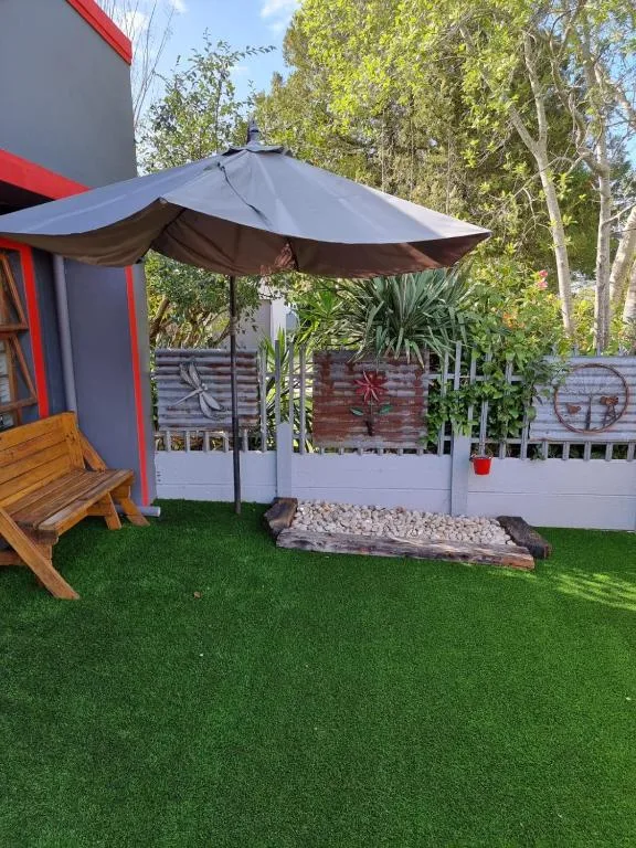 Shaded outdoor patio area with large umbrella and wooden seating