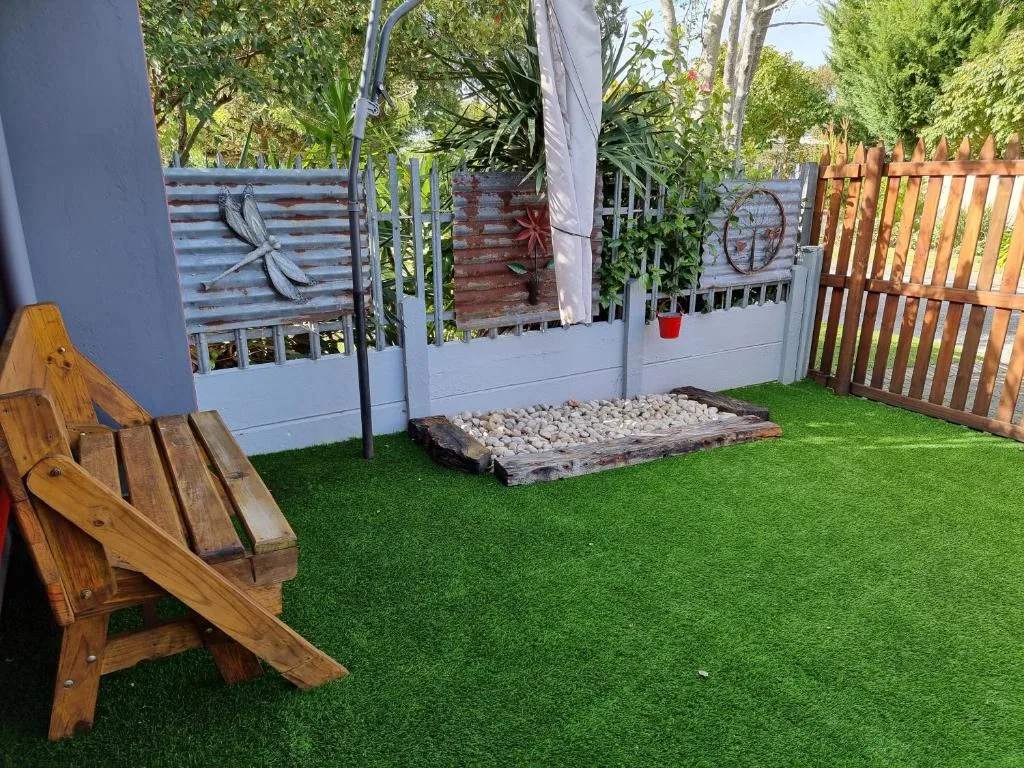 Backyard patio with wooden chair, artificial turf, and garden fencing