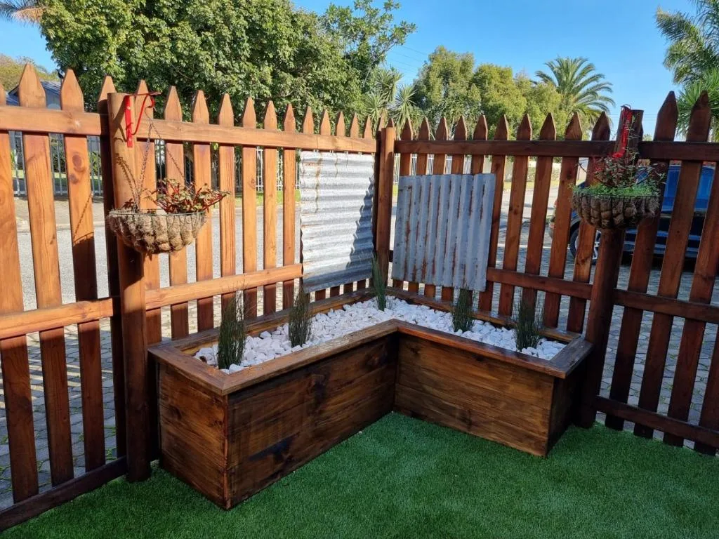 Wooden raised garden beds with white gravel and green plants in courtyard