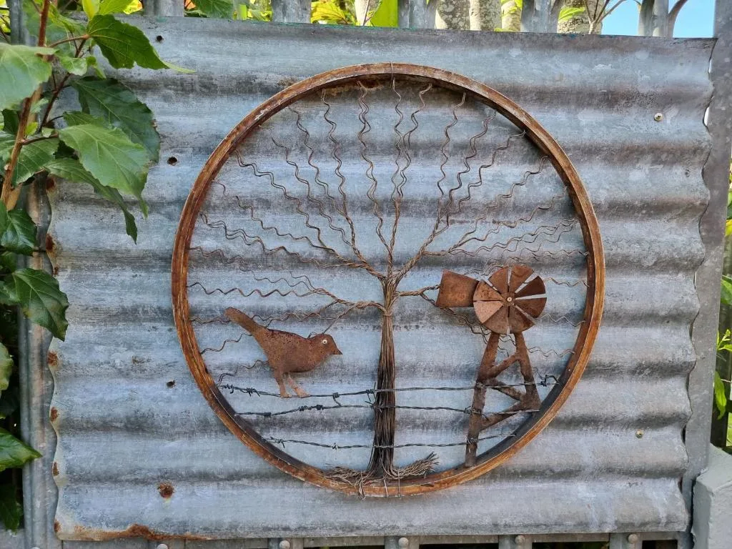 Rustic metal tree and windmill wall art on corrugated iron backdrop