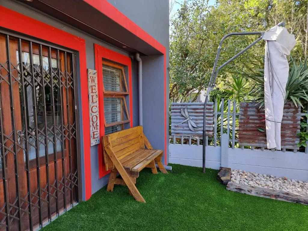 Colorful red and blue cottage exterior with wooden chair and garden entrance