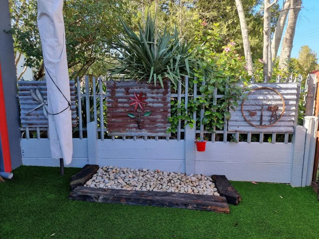 Garden area with white fence, decorative metal art, and landscaping