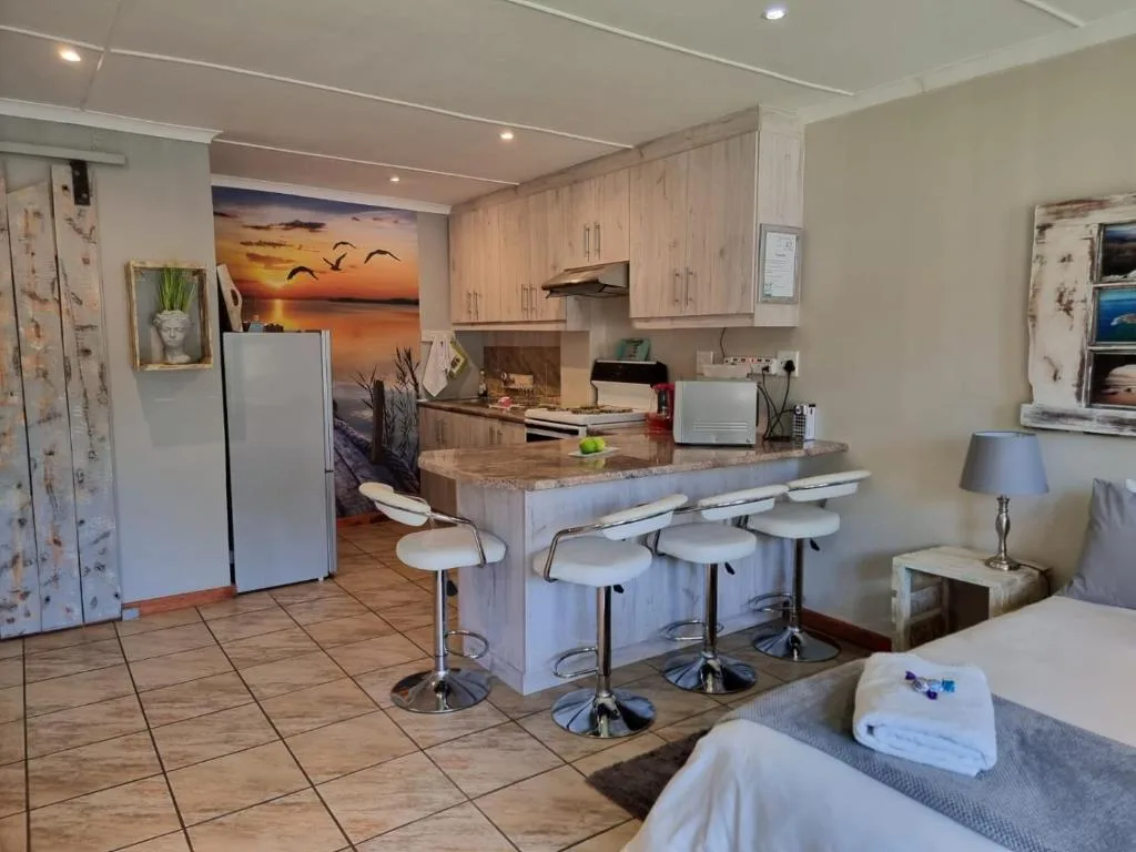 Open-plan kitchen with light wood cabinetry, island counter and bar seating