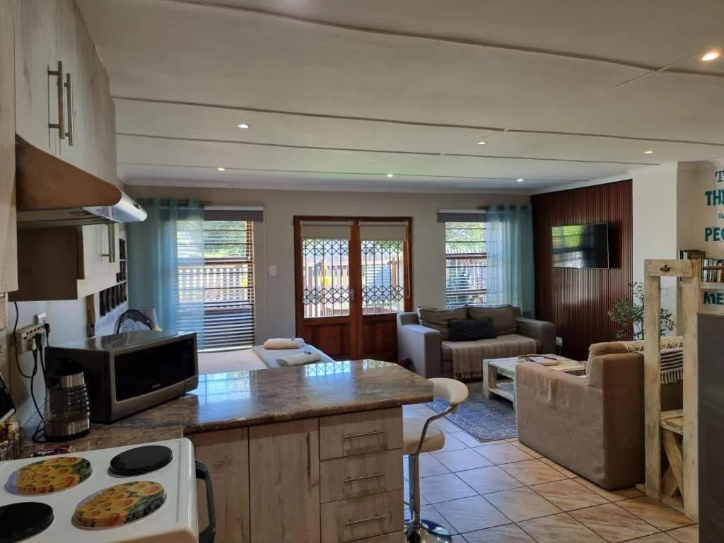 Open-plan lounge with beige sofas, TV, and ocean view doors