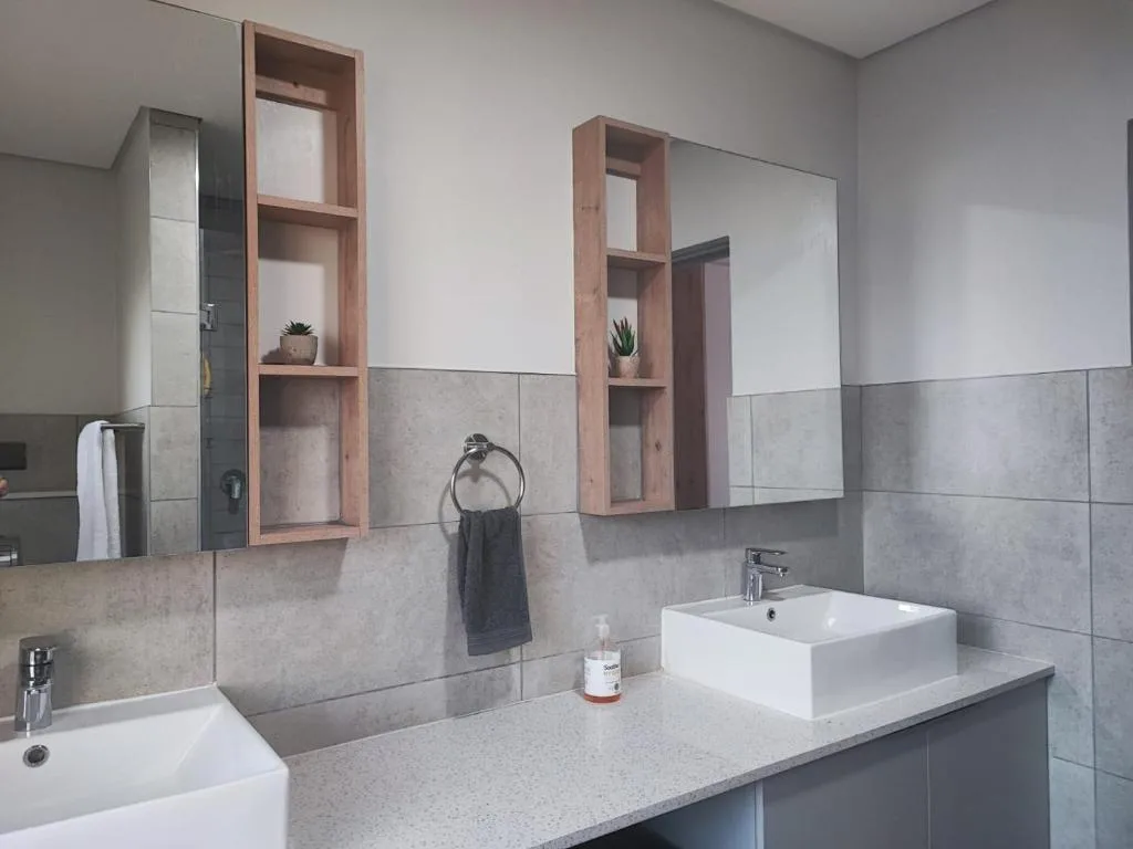 Modern bathroom with dual vanity, white vessel sinks, and wooden shelving