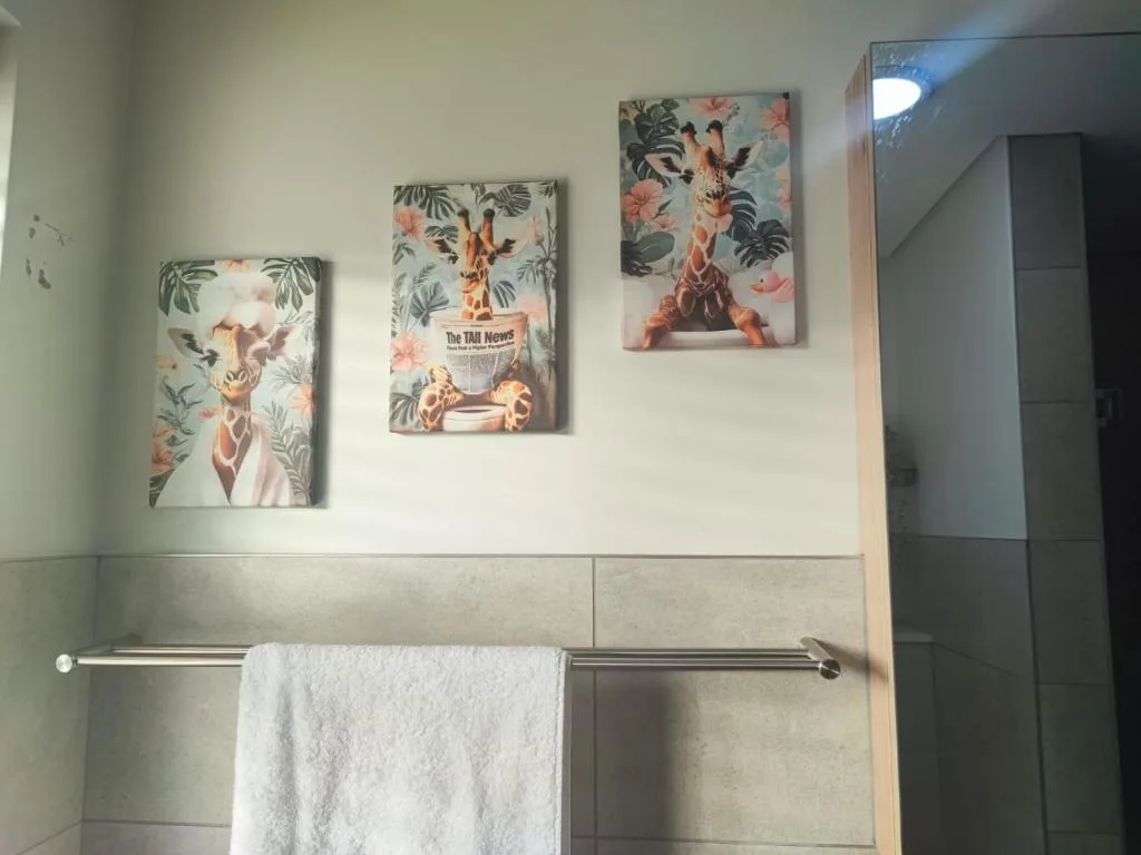 Modern bathroom with tile walls, towel rail, and whimsical giraffe artwork
