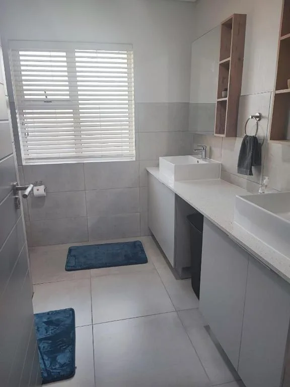 Modern bathroom with dual vanity, vessel sink, and white tile flooring