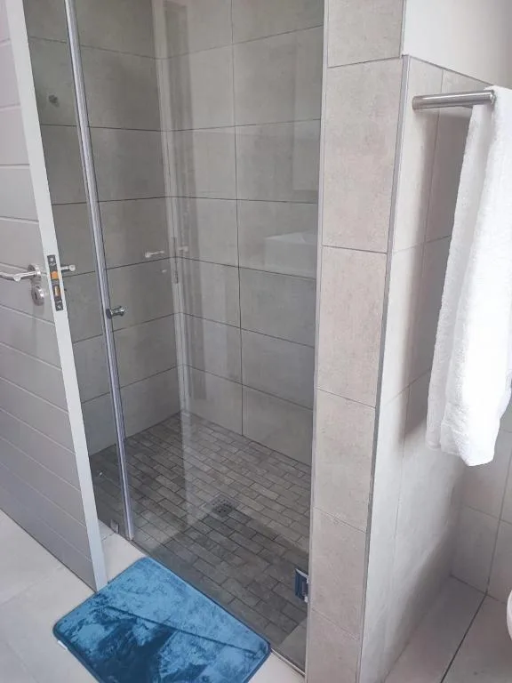 Modern shower enclosure with grey tile walls and heated towel rail