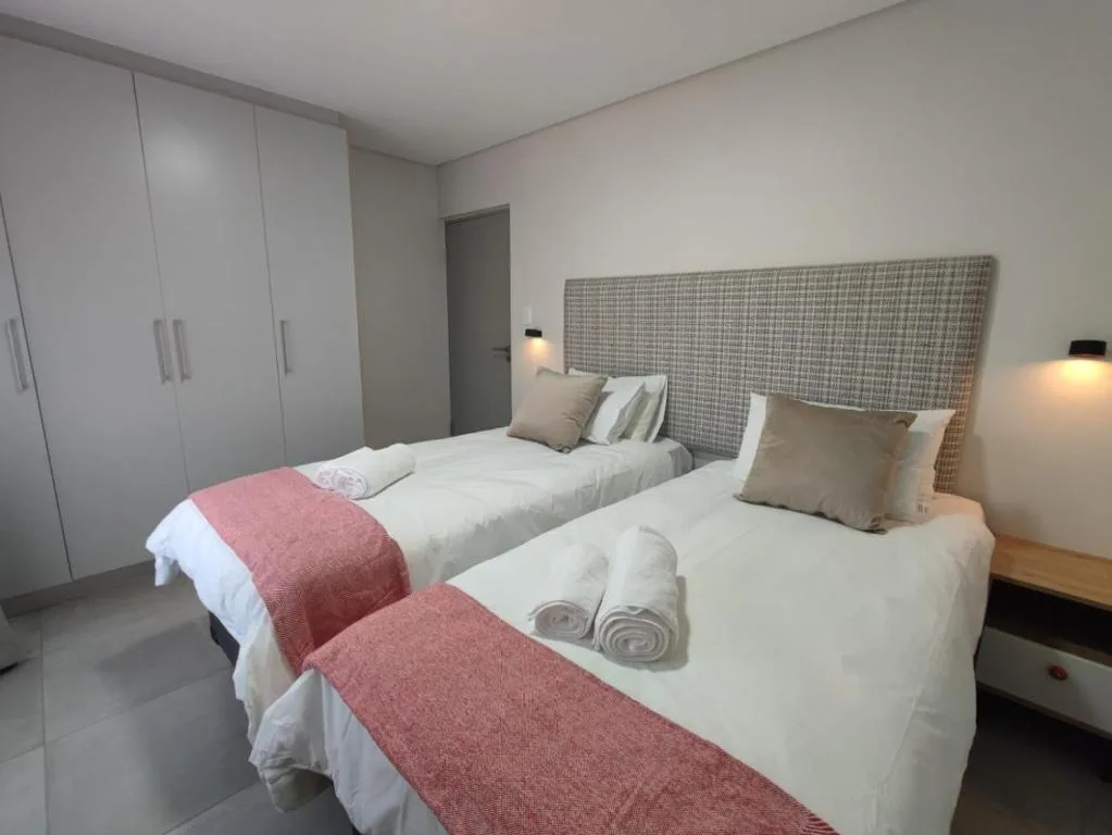 Twin beds with white linens and red throws in modern bedroom