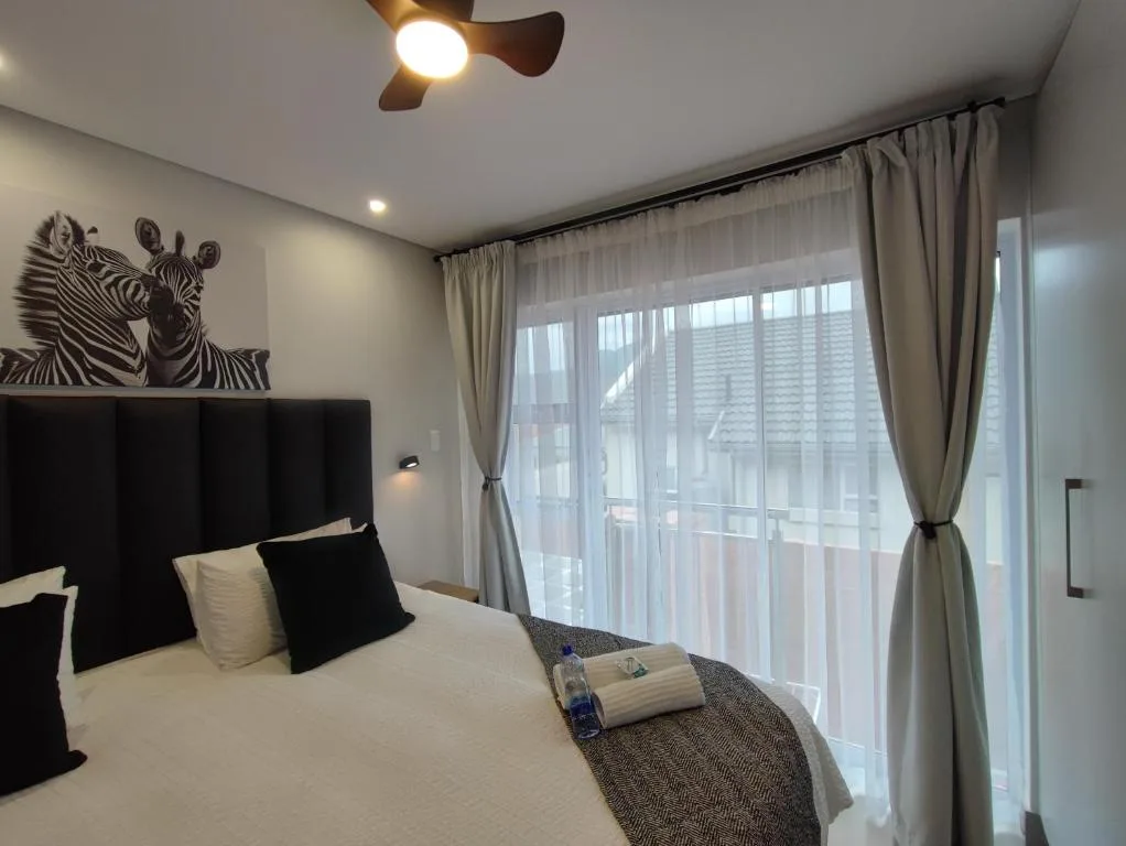 Modern bedroom with black upholstered headboard and zebra artwork above