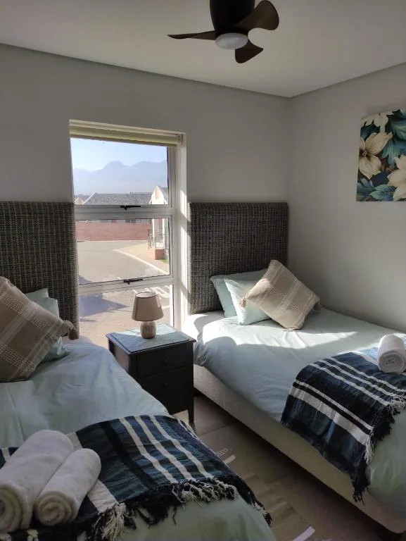 Twin bedroom with mountain views through glass door and ceiling fan