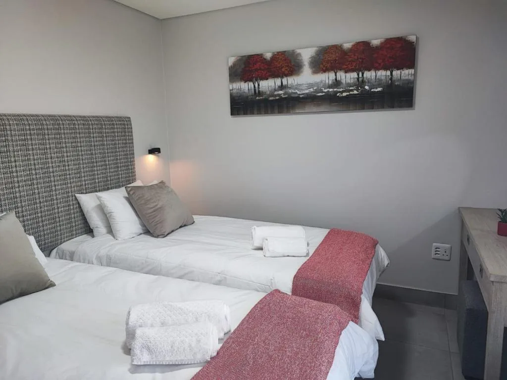 Twin bedroom with patterned headboard, white bedding, and wall art